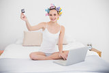 Relaxed natural brown haired woman in hair curlers shopping online with a laptop