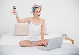 Excited natural brown haired woman in hair curlers shopping online with her laptop