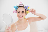 Attractive natural brown haired woman in hair curlers applying mascara