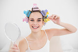 Happy natural brown haired woman in hair curlers brushing her eyebrows