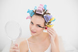 Beautiful natural brown haired woman in hair curlers applying mascara