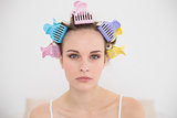 Stern natural brown haired woman in hair curlers looking at camera