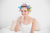 Content natural brown haired woman in hair curlers drinking water