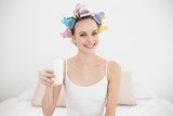 Casual natural brown haired woman in hair curlers holding a glass of milk
