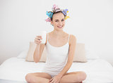 Pretty natural brown haired woman in hair curlers holding a glass of milk