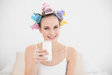 Beautiful natural brown haired woman in hair curlers holding a glass of milk