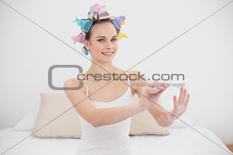 Pretty natural brown haired woman in hair curlers filing her nails