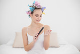Focused natural brown haired woman in hair curlers filing her nails