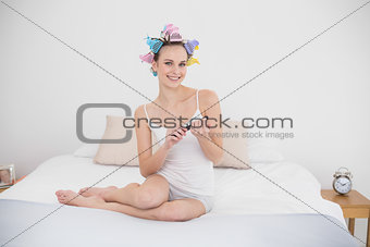 Relaxed natural brown haired woman in hair curlers filing her nails