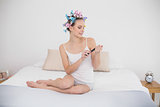 Attentive natural brown haired woman in hair curlers filing her nails