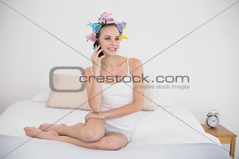 Dreamy natural brown haired woman in hair curlers making a phone call