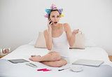 Shocked natural brown haired woman in hair curlers calling with her mobile phone