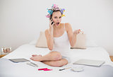 Astonished natural brown haired woman in hair curlers calling with her mobile phone