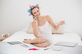 Amused natural brown haired woman in hair curlers calling with her mobile phone