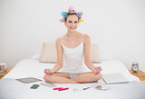 Content natural brown haired woman in hair curlers relaxing in lotus position