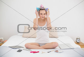 Anxious natural brown haired woman in hair curlers looking at camera