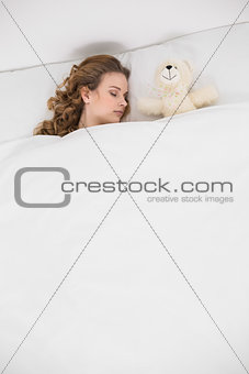 Pretty brunette sleeping next to teddy bear