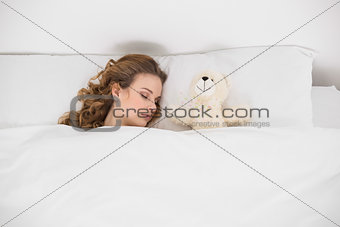Attractive brunette sleeping next to teddy bear