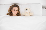 Beautiful brunette sleeping next to teddy bear