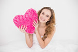 Happy attractive brunette holding heart pillow