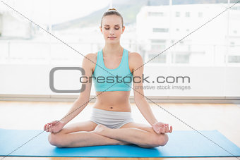 Sporty peaceful woman sitting cross-legged on exercise mat