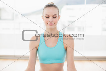 Sporty smiling woman sitting with closed eyes
