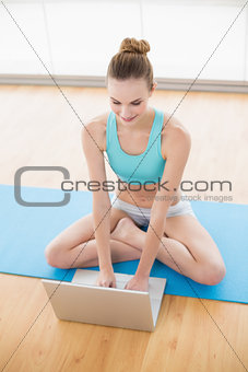 Sporty cheerful woman using laptop