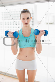 Sporty serious woman holding dumbbells