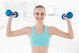 Sporty happy woman holding up dumbbells