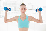 Sporty serious woman holding up dumbbells