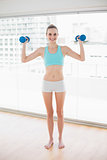 Sporty smiling woman holding up dumbbells