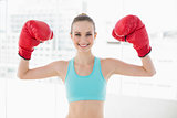 Sporty smiling woman holding up boxing gloves