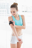 Sporty happy woman pressing a button on mp3 player