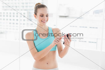 Sporty smiling woman touching smartphone