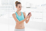 Sporty calm woman holding smartphone