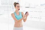 Sporty surprised woman holding smartphone