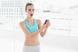 Sporty shocked woman holding smartphone