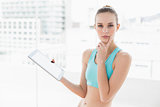 Sporty pensive woman holding a tablet