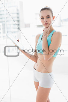 Sporty thoughtful woman holding a tablet