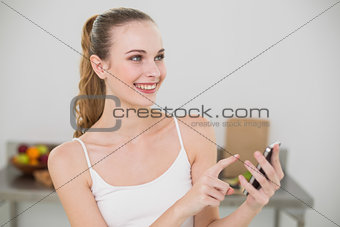 Smiling young woman holding smartphone