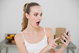 Shocked young woman holding smartphone