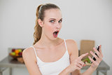 Astonished young woman holding smartphone