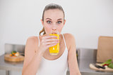 Cheerful young woman drinking glass of orange juice