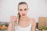 Serious young woman holding glass of water