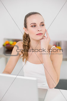 Thoughtful young woman using her laptop