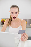 Shocked young woman using her laptop for online shopping