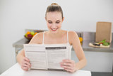 Happy young woman reading a newspaper