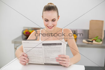 Happy young woman reading a newspaper