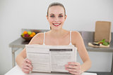 Smiling young woman holding a newspaper