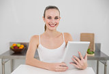 Smiling young woman using her tablet pc looking at camera